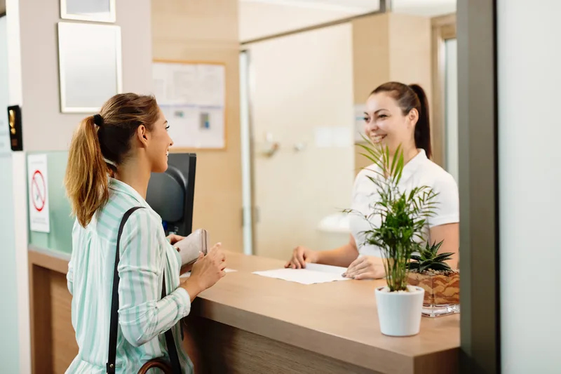 Patiente accueillie par une secrétaire à l’accueil d’un centre médical